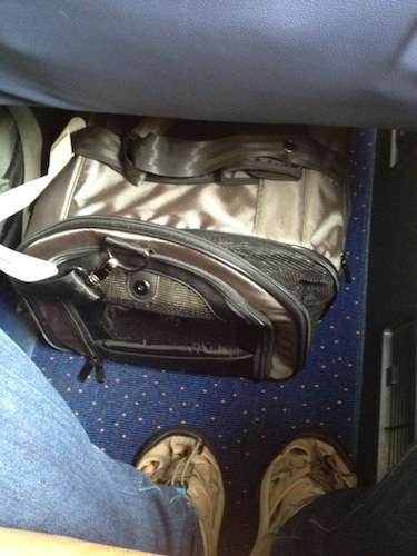 The large Kobi carrier, still under the same seat, but now with the end gusset unzipped. Because the center of the bag needs to squish a little to dodge the under-seat fixtures, the ends are pulled inwards and you can't see the entire gusset.